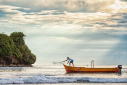 Man casting his fishing net at sunrise in Puerto Viejo, Costa Rica