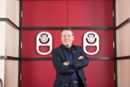 Cott Beverages CEO Jerry Fowden standing in front of large red door at the Cott headquarters in Tampa - Carver Mostardi Photography - Tampa corporate portraits.