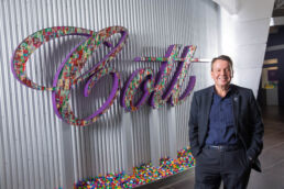 Cott Beverages CEO Jerry Fowden standing next to Cott sign in Tampa headquarters - Carver Mostardi Photography - Tampa corporate portraits.