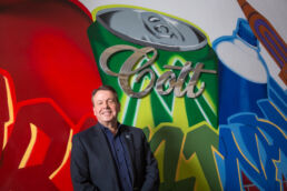 Cott Beverages CEO Jerry Fowden in front of Cott sign and graffiti art work in their Tampa headquarters - Carver Mostardi Photography - Tampa corporate portraits.