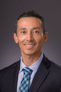 Formal portrait of engineer in suit against gray photographed onsite at his office in Tampa.