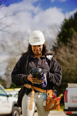 Female telecommunications service technician with hard hat checking equipment onsite in suburban Philadelphia.