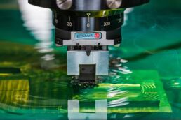 Close up of metal machining in the green dielectric fluid of a Makino CNC electrical discharge machine or EDC.