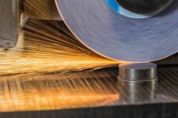 Sparks shoot from metal grinding disc finishing parts at an Orlando industrial machine shop.