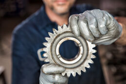 Close up of auto service tech with silver gloves holding automotive transmission gear in Riverside, Fl.