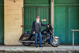 Editorial portrait of older man with long white beard and Harley Davidson motorcycle in downtown Ybor City, Tampa, Florida.