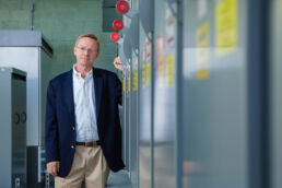 Leadership team member in blue blazer with electrical panels at electric plant in Philadelphia, PA.