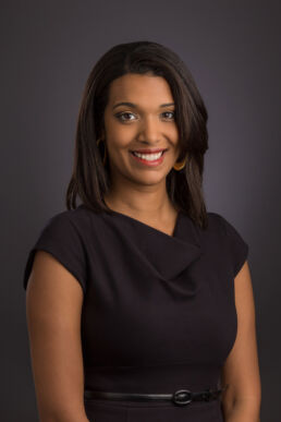 Female African American executive headshot with black dress against dark gray in Tarpon Springs, Florida.