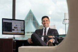 environmental portrait of Tampa attorney sitting in office with view skyline through large windows