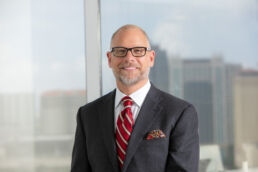 Male attorney photograph in suit and tie with city skyline at law firm office in downtown Tampa.