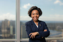 Female African American attorney photographed onsite at Tampa law firm with city skyline in the background.